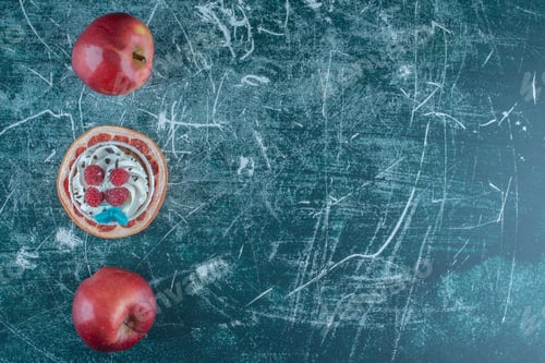 Preview: Two apples and a cupcake on a slice of grapefruit on blue background