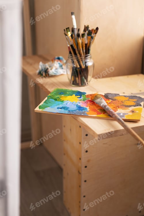Preview: Painting palette and paint brush in glass jar on wooden table or windowsill. Art still life