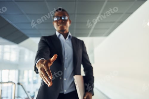 Preview: Handshake gesture. Young african american businessman in black suit is indoors