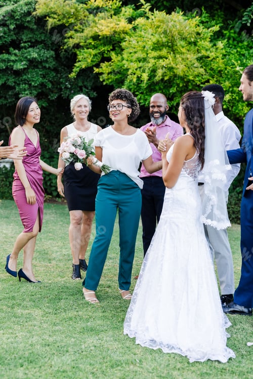 Preview: Diverse group celebrating wedding festivities outdoors with joyful expressions