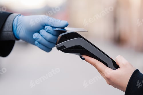 Preview: Hand in rubber gloves, credit card and payment terminal. Prevention of coronavirus spread