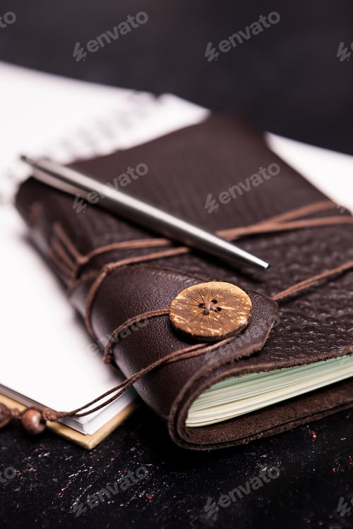 Preview: Leather covered vintage ntoebook on an open diary