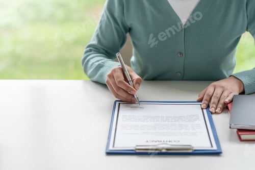 Preview: Close-up of businesswoman holding pen signing contracts at the office.