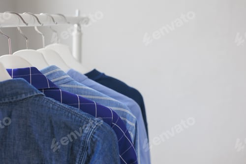 Preview: Neat Row of Blue Shirts Hanging on Rack