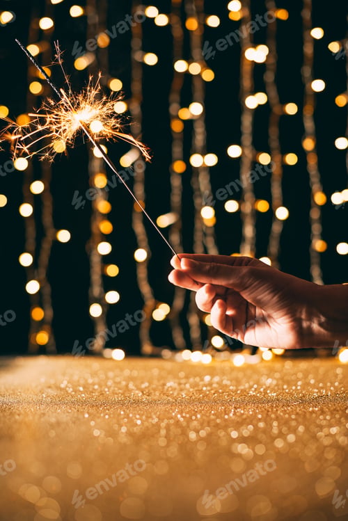 Preview: cropped image of woman holding christmas sparkle on garland light background