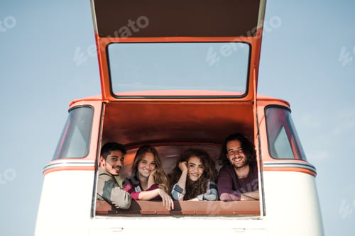 Preview: A group of young friends on a roadtrip through countryside, looking out of window.