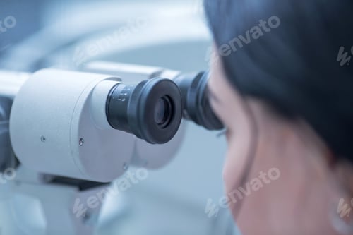 Preview: a young ophthalmologist woman looks into the viewfinder of a slit lamp