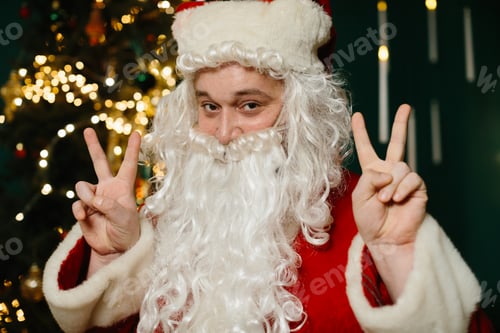 Preview: Santa claus making victory sign in christmas atmosphere