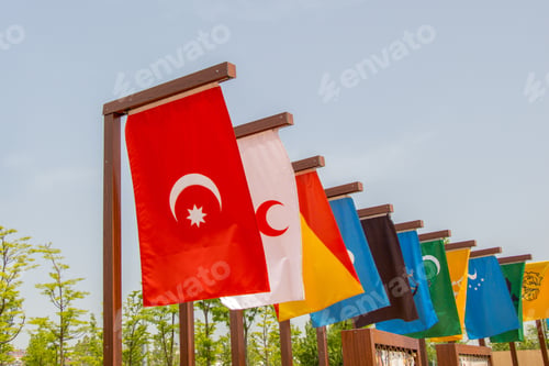 Preview: Closeup of different flags of Islamic countries on flagpoles under a cloudy sky