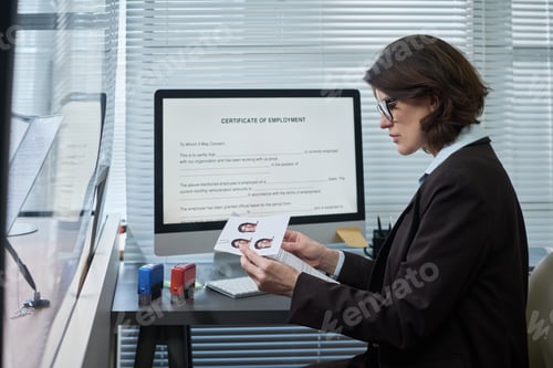 Preview: Middle Aged Woman Reviewing Passport Photos at Visa Center Desk