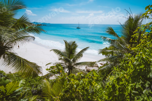 Preview: Holiday vacation at Petite Anse paradise beach framed by green foliage. La Digue island, Seychelles