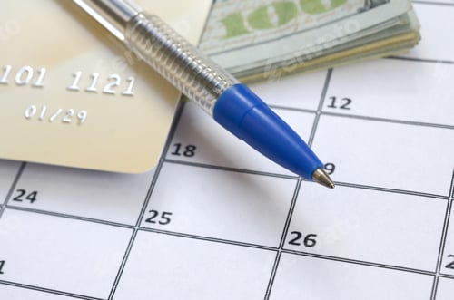 Preview: Pen and credit card on many hundred US dollar bills on calendar page close up