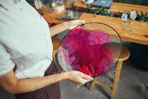 Preview: Professional painter examining a beautiful abstract painting in her hands