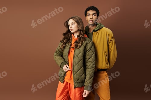 Preview: Young couple showcases vibrant autumn fashion in warm colors against a rich backdrop