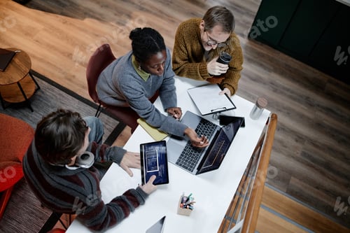Preview: Diverse Young Adults Collaborating on Project Using Laptop in Modern Office