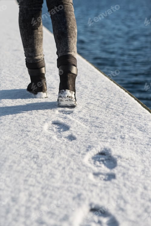 Preview: Low section of woman walking on snow covered footpath by canal