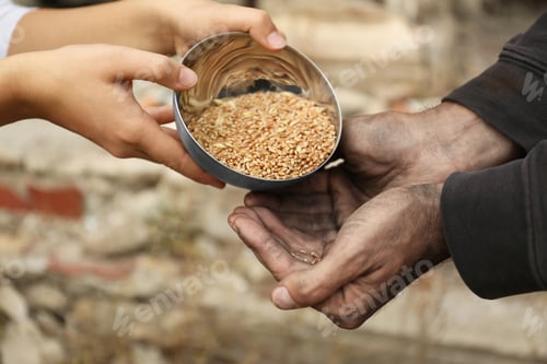 Preview: Woman giving poor homeless man bowl of wheat outdoors, closeup