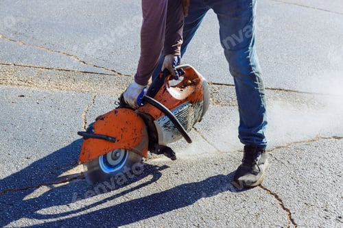 Preview: An asphalt in parking lot is cut using diamond blade saw machine by a construction worker