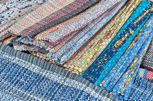 Preview: Homemade colourful woven rugs made of fabric ribbons stacked. Close-up.