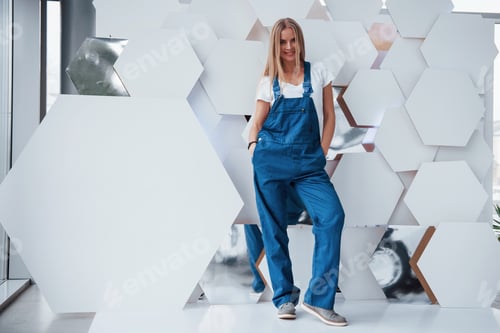 Preview: Girl in blue uniform stands against abstract wall with white pieces of surface