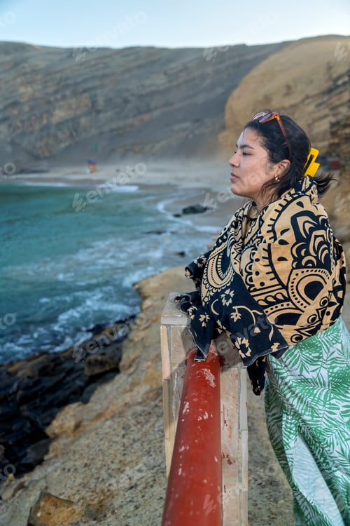 Preview: Tourist enjoying the sunset at the beach wrapped in a patterned blanket
