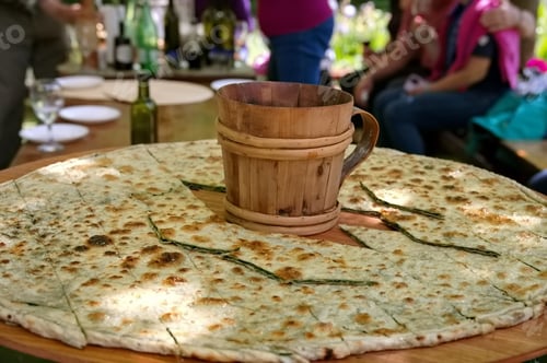 Preview: Soparnik - traditional Croatian food on big wooden plate with wooden mug in the middle