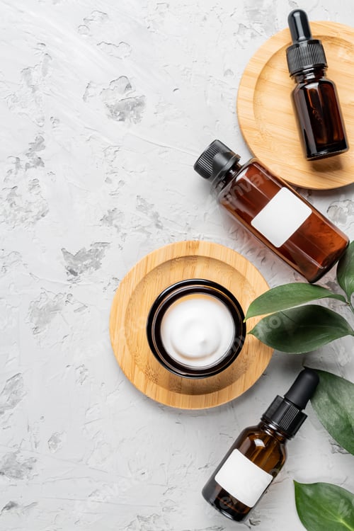 Preview: Amber glass bottle of organic cosmetics and green plant leaf on gray concrete background. SPA natura