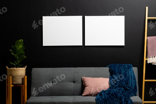 Preview: White empty frames with copy space and plant on black wall in room with couch
