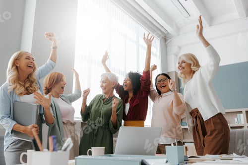Preview: Group of happy businesswomen gesturing and smiling while having meeting in office