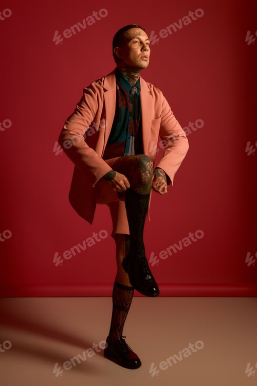 Preview: Stylish man posing confidently against a vibrant red backdrop showcasing modern fashion trends