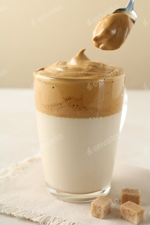 Preview: Taking cream from delicious dalgona coffee and brown sugar at light table, closeup