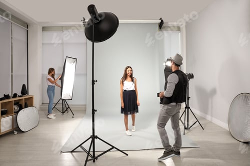 Preview: Professional photographer and assistant working with model in modern studio