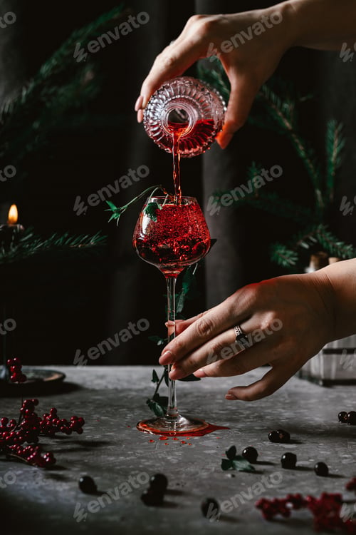 Preview: Women's hands pour red champagne into a glass in a winter atmosphere in a low heat. Winter mystery.
