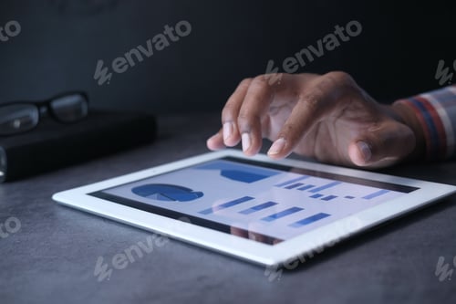 Preview: man's hand working on digital tablet at office desk, using self created chart