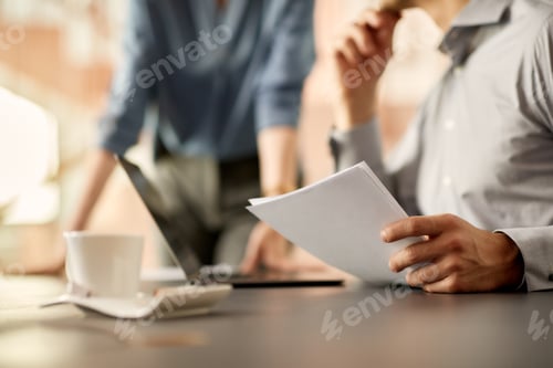 Preview: Close-up of businessman analyzing reports with colleague in the office.