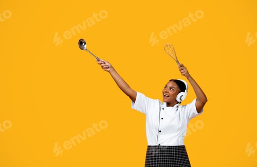 Preview: Happy Black Chef Woman In Headphones Dancing On Yellow Studio Background