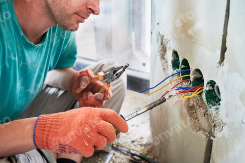Preview: Male electrician using electric soldering iron in apartment.