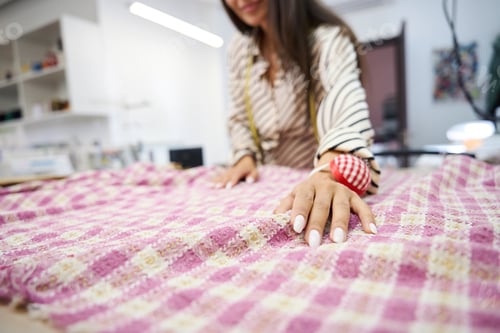 Preview: Designer lays out plaid fabric on the cutting table