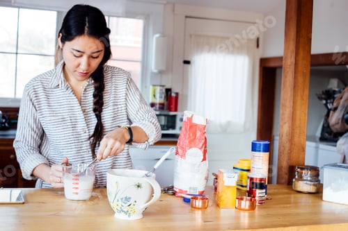 Preview: Woman in kitchen preparing waffle batter