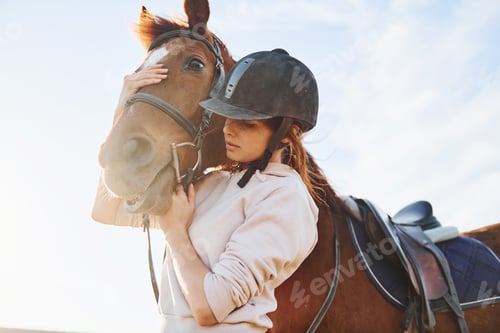 Preview: Beautiful sunshine. Young woman standing with her horse in agriculture field at daytime