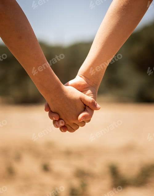 Preview: Beautiful closeup shot of a couple holding hands on a blurred background of a field