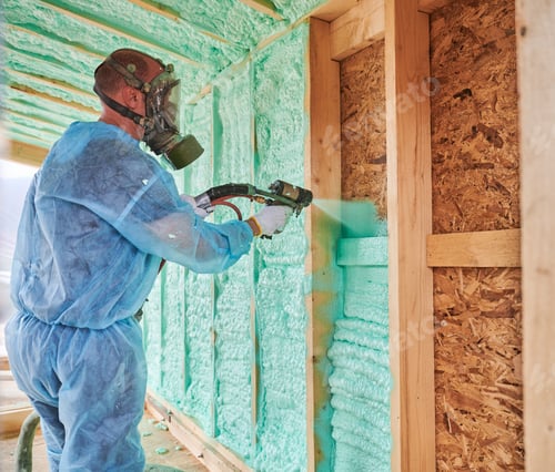 Vorschau: Arbeiter sprühen Polyurethanschaum zur Isolierung des Holzrahmenhauses.
