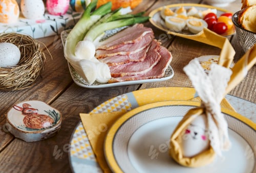Preview: Close-up image of Easter egg decorated as easter bunny. Table full of delicious food.