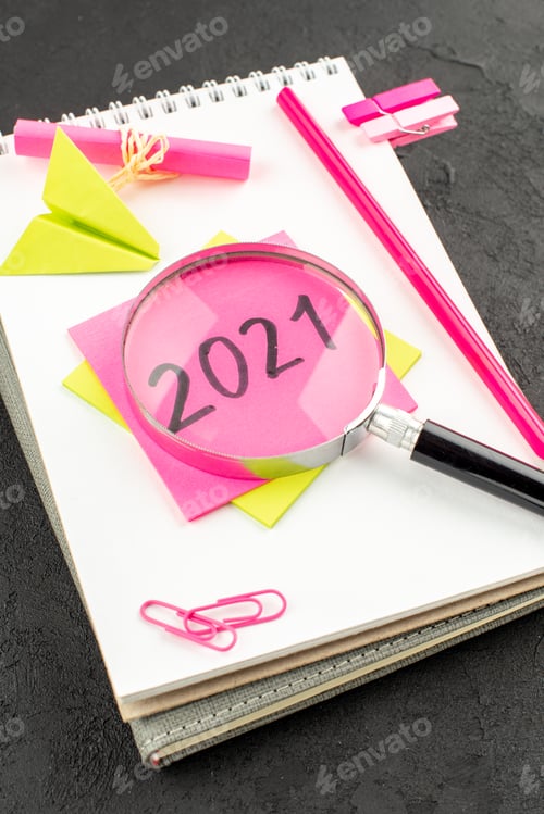 Preview: bottom view pink pencil written on sticky note on spiral notepad gem clips on dark background