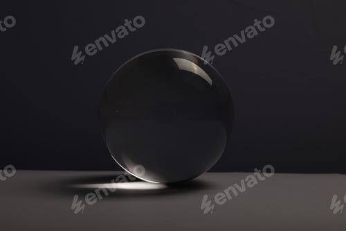 Preview: Transparent glass ball on table against dark background