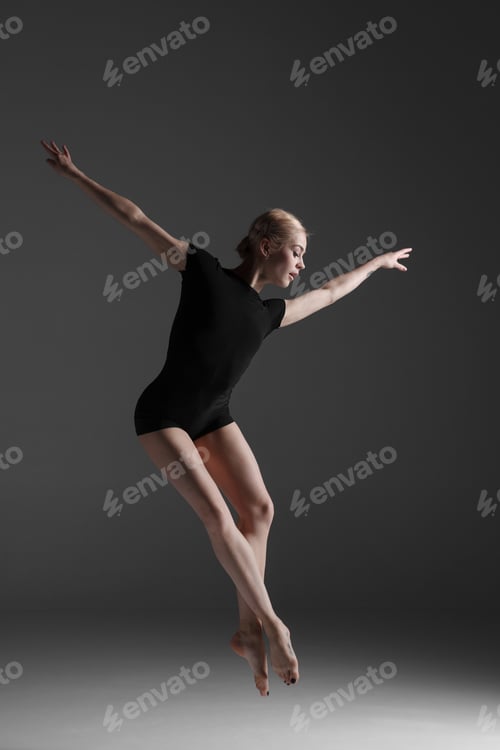 Preview: Young Beautiful Modern Style Dancer Jumping On A Studio Gray Background