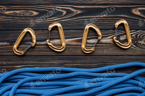 Preview: Isolated photo of climbing equipment. Part of carabiner lying on the wooden table
