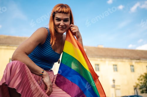 Preview: Young activist showing rainbow flag at gay pride parade promoting lgbtq rights and equality