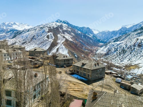 Preview: Rustic village houses in a vast valley with towering snowy mountains