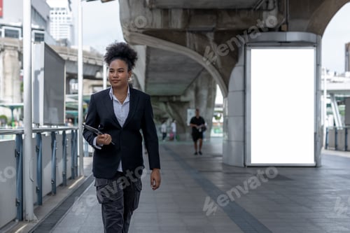 Visualização: Empresária adolescente, africana americana, penteado afro segurando um tablet andando pela cidade